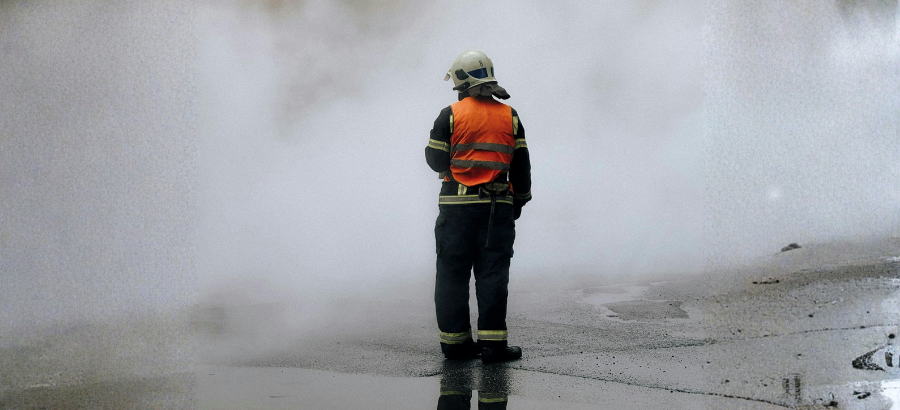 First responder in gear standing in front of white smoke