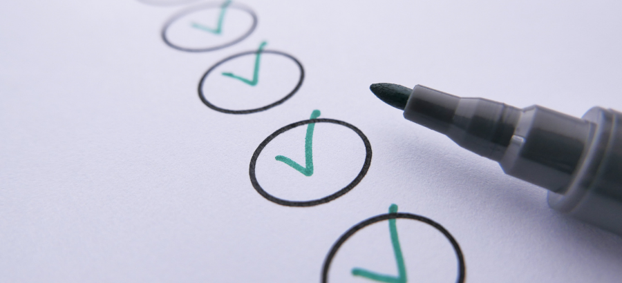 Checklist with green check marks being completed using a marker