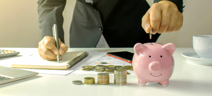 Man in formal clothes dropping coin into piggy bank